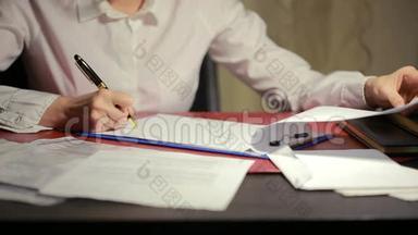 女人的手在纸上写一支钢笔。