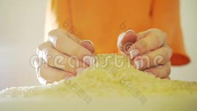 穿着橙色衣服的女人用手舀米堆，慢动作视频