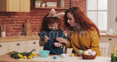 复活节快乐。 妈妈教女儿画鸡蛋。 为复活节<strong>做准备</strong>的幸福家庭。 小女孩戴着兔耳朵