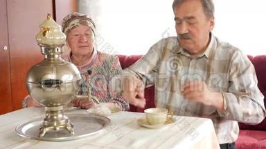 一对老夫妇用一个老式的俄罗斯水壶萨莫瓦尔准备茶。 一个留胡子的男人给妻子倒茶