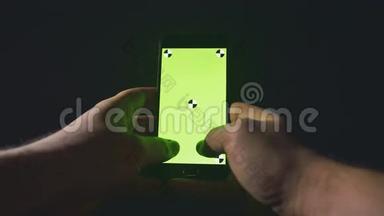 特写年轻人手打字短信滚动图片手机。 晚安。 绿色屏幕。 铬钥匙。