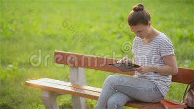 可爱的年轻女人在公园里<strong>拿</strong>着<strong>平板</strong>电脑，漂亮的女人在花园里的长凳上<strong>拿</strong>着<strong>平板</strong>电脑，年轻的女学生。