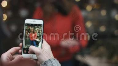 一个男人在户外为他迷人的女孩拍照的特写镜头。 他用手机拍照