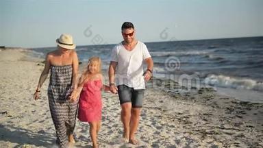 快乐的一家人和小女儿在海滩上散步，在海边的暑假里牵手。