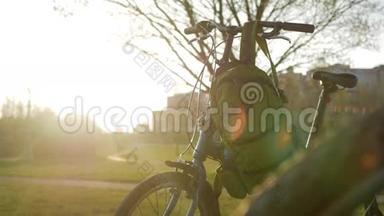 <strong>折叠自行车</strong>站在公园日落时。 上面挂着绿色背包