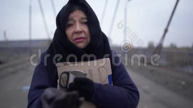 在寒冷、多风、灰色的天气里，老乞丐在桥上请求施舍和帮助