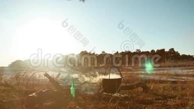 剪影点燃篝火徒步旅行者停在露营地徒步旅行者水壶里的水沸腾在夕阳的剪影中点燃阳光
