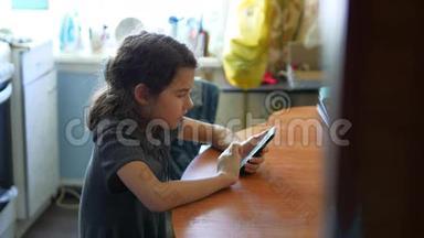 女孩早餐在厨房社交媒体玩智能手机网络游戏坐在桌子旁。