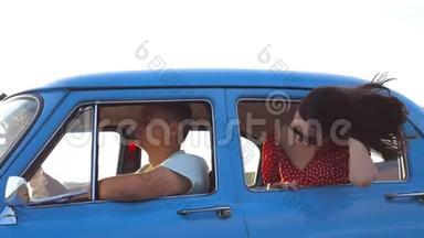 戴墨镜的快乐女孩斜倚在复古车窗外，享受旅行。 年轻女子望着窗外移动的老人