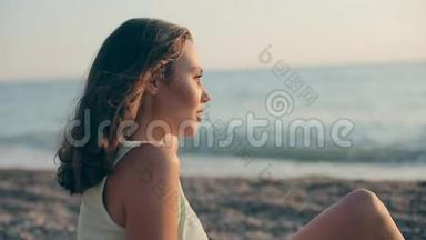快乐的女孩坐在海边的鹅卵石上，若有所思地向远方望去