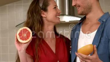 微笑的年轻夫妇抱着一半的葡萄柚