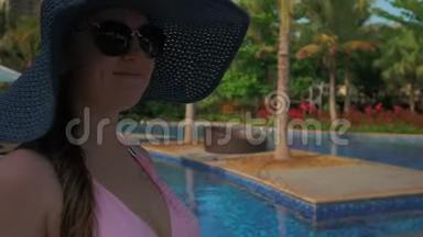 戴着蓝<strong>帽子</strong>的漂亮女孩在游泳池边散步。 <strong>夏日</strong>的阳光。 慢动作