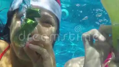 有趣的女孩穿着圣诞老人的帽子在泳池里潜水，在苏梅岛度过圣诞假期