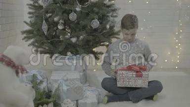 欢乐的<strong>小男孩</strong>在装饰的<strong>新年</strong>树节日气氛室内打开圣诞礼物盒