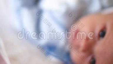 一个可爱的小宝宝正看着相机，在一张白色的床单上很开心。 婴儿环顾四周，然后微笑