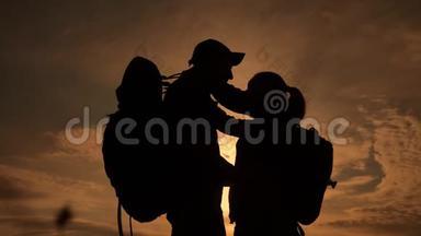幸福的家庭游客剪影在日落拥抱接吻。 团队合作旅游概念。 男女夫妻生活方式