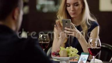 年轻夫妇在餐馆约会时使用智能手机