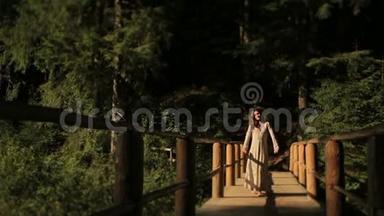 美丽的赤脚女子，穿着刺绣的传统长裙，走在喀尔巴阡山的木桥上，晒太阳