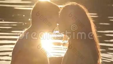 两个情人在晚上的背景下在湖边接吻的剪影。 宁静的浪漫时刻