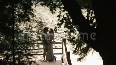 一对幸福的年轻夫妇站在湖边的山上，轻轻地拥抱着。 喀尔巴阡山脉，乌克兰