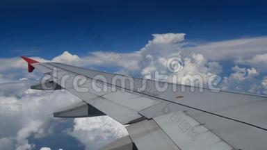 4K镜头飞机飞行。 在白云和蓝天上空飞行的飞机的翅膀。 窗外美丽的鸟瞰图