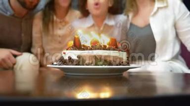 快乐的微笑男孩在她的生日蛋糕上吹<strong>蜡烛</strong>。 被家人包围的孩子。 有<strong>蜡烛</strong>的生日蛋糕