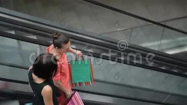 年轻漂亮的快乐女人在商场的自动扶梯上，女孩在商店里购物