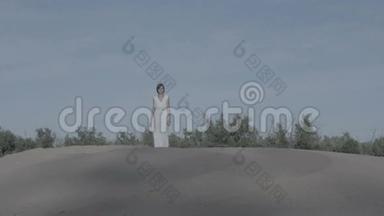 穿着白色连衣裙的女人走在没有等级的沙子上