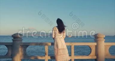 美丽的高加索女人在日落时看海景。 年轻美丽的女孩享受大自然，看着海洋