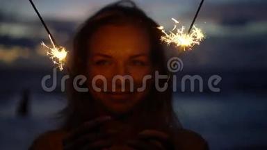 黄昏时分，在海滩上燃放烟花的幸福女人特写