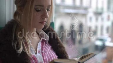 美丽的年轻女子坐在窗台上，<strong>看</strong>书，<strong>看</strong>着<strong>窗外</strong>