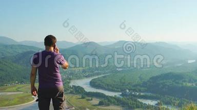 俄罗斯阿尔泰山地风景背景下的一个人在手机上讲话