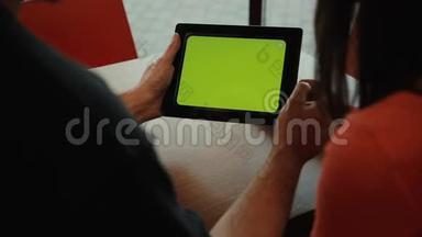 一对夫妇在咖啡馆里用平板电脑。 绿色屏幕