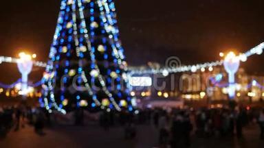新年前背景镇广场模糊。 城市居民围绕圣诞树举行的晚间庆祝活动