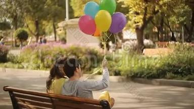 一对拿着气球坐在公园的长凳上