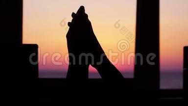 一个男人和一个女人互相牵着手，在窗前的大海和美丽的日落的背景下。 慢慢慢慢