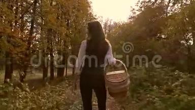 瘦削的黑发女孩走在秋天的森林里，拿着一个野餐篮。 4Ksteatam视频