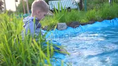 那个男孩坐在一个小湖边。 这孩子用脚造成水溅. <strong>夏日炎炎</strong>。 快乐的童年
