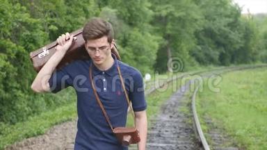 一个在铁路线上带着手提箱的年轻人。 火车在<strong>大城</strong>市里迷路，年轻人在<strong>大城</strong>市里迷路