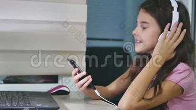 少女在音乐耳机里唱歌。 女生在网上听音乐，在室内跳舞唱歌