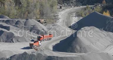 自卸卡车在花岗岩采石场行驶，在采石场用重型机械开采石块