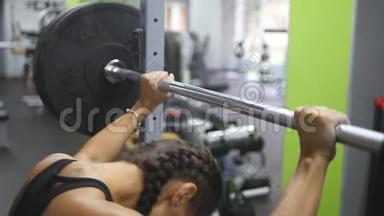 年轻女子的肖像准备在健身房举起沉重的杠铃。 女运动员举重杠铃
