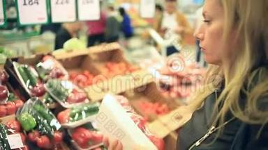 一个女人在蔬菜货架上的<strong>超市</strong>里买蔬菜和<strong>水果</strong>。 男人选择番茄