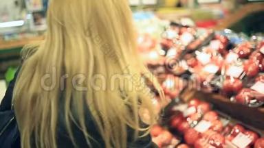 一个女人在<strong>蔬菜</strong>货架上的超市里买<strong>蔬菜</strong>和<strong>水果</strong>。 男人选择番茄