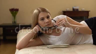 年轻漂亮的女人躺在沙发上。 在智能<strong>电视</strong>上安装3d眼镜开关，<strong>观看</strong>3d电影