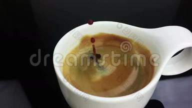 咖啡滴在咖啡杯中缓慢运动，咖啡中有黑色背景的泡沫，食物和饮料