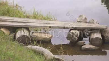 从平静的河流中建造的原木和石头制成的自制木桥。