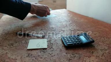 男人数着钱放在桌子上。 双手特写。