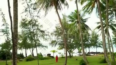 Phu Quoc。 漫步在热带花园里.. 美丽的女人穿着红色衣服在热带花园散步。 在热带岛屿