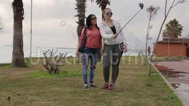 两名年轻女子使用智能<strong>手机手机</strong>相机在海滨<strong>拍摄</strong>自我肖像。